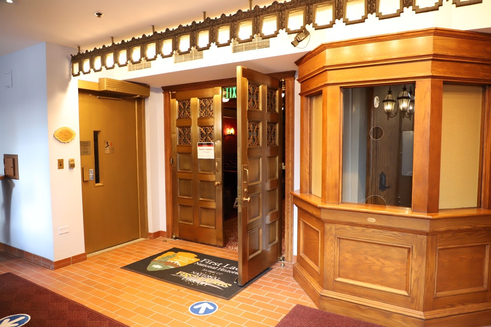 Brass doors opening to revel a peak of an historic theater. 