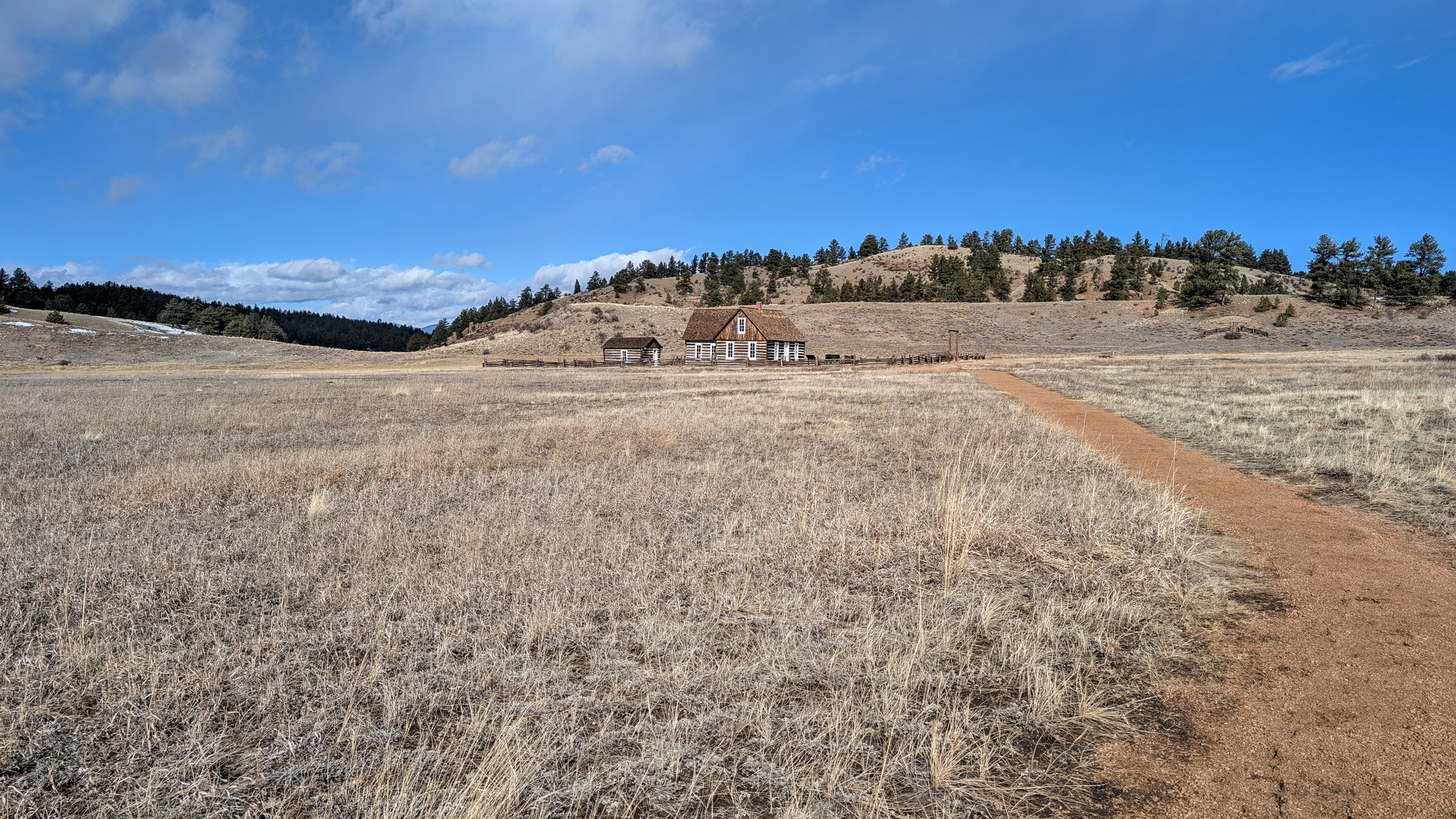 A granite trail cuts through a valley toward a historic homestead.
