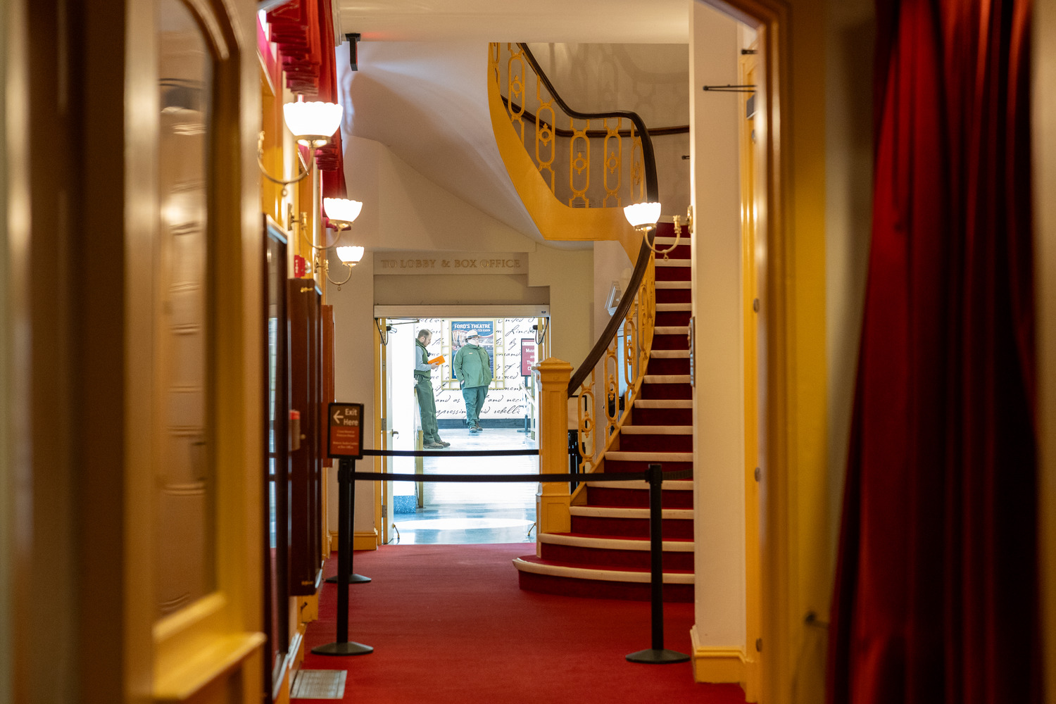 A hallway with doors on either side leading to a curved staircase over an open doorway.