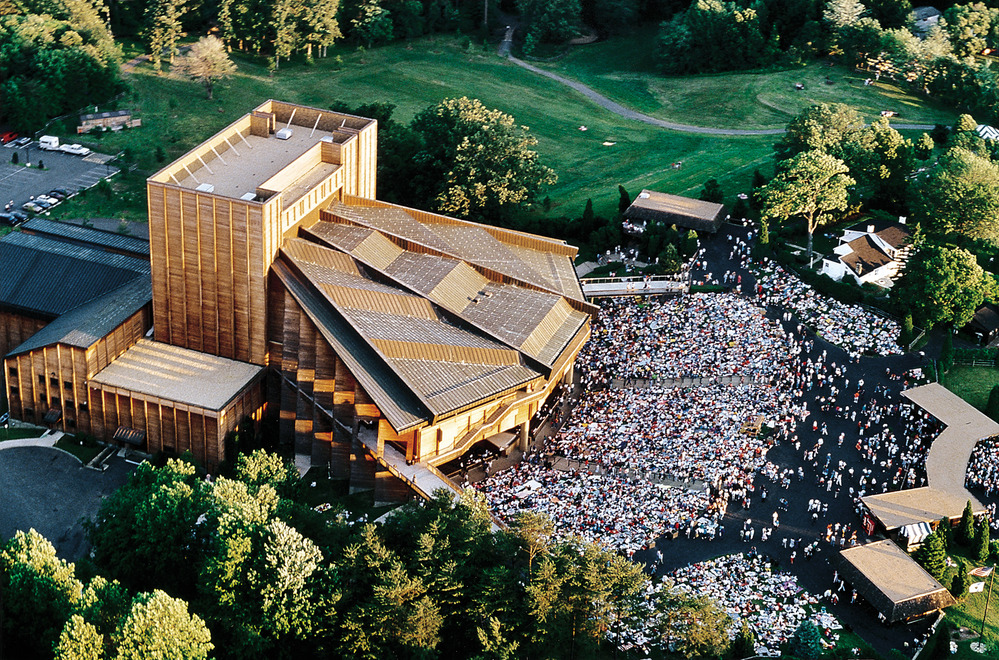 An aerial view of the Filene Center with several hundreds of people surrounding it. 